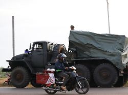 a man drives past a military vehicle heading towards the border amid deadly clashes between thailand and cambodia along a disputed border area in srei snam siem reap province cambodia december 10 2025