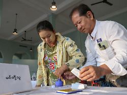 a polling official assists a woman during voting at kyauktada township polling station no 1 on the day of general elections in kyauktada myanmar december 28 2025
