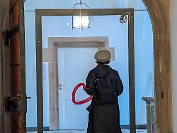 a woman holds a red heart shaped balloon and stands in front of a white door inside a historic building in munich bavaria germany on may 3 2025 the image centers on the symbol of the heart