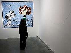 a woman looks at snoopy art work displayed as part of the snoopy in style exhibition to mark the peanuts comic strip s 75th anniversary in paris france march 20 2025