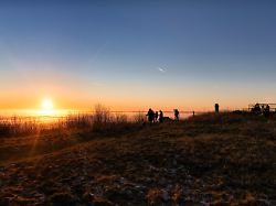 besucher geniessen die letzten sonnenstrahlen auf einem berggipfel im weserbergland
