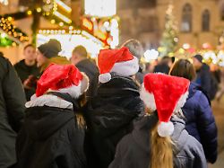 besucher mit weihnachtsmannmuetzen laufen ueber den hildesheimer weihnachtsmarkt auf dem historischen marktplatz
