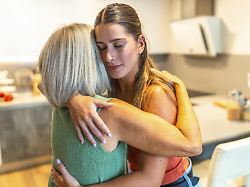 die erwachsene tochter umarmt ihre aeltere mutter und spendet ihr trost und unterstuetzung in einem herzerwaermenden moment zu hause modellfreigabe vorhanden