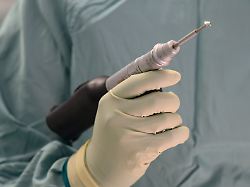 ein arzt haelt in einem operationssaal eine bohrmaschine in der hand symbolbild