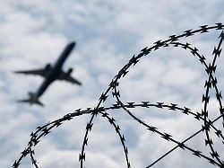 ein flugzeug startet hinter einem zaun mit natodraht