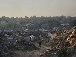 ein mann geht eine strasse mit gebaeuden entlang die bei israelischen luft und bodenoperationen zerstoert wurden