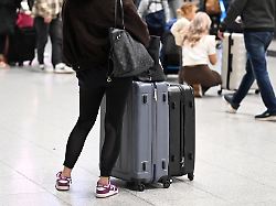 ein reisende schiebt ihre koffer im abflug terminal des flughafen zu beginn der herbstferien viele reisende nutzen die ferien um den trueben herbstwetter zu entfliehen