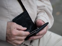 ein rentner haelt sein portemonnaie in der hand