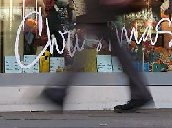 eine passantin geht an einem kaufhaus mit einem weihnachtlich geschmueckten schaufenster und der aufschrift christmas vorbei