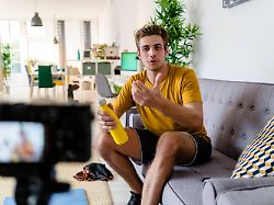 fitness trainer live streaming fitness session while sitting on sofa at home model released symbolfoto property released giof08953