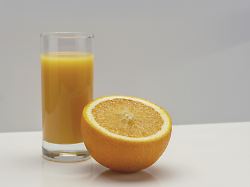 glas orangensaft und die haelfte einer grossen orange auf weissem glas kopierraum