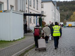 neuangekomme fluechtlinge gehen mit ihren koffern in eines der wohnhaeuser der aufnahmeeinrichtung fuer asylbegehrende afa in trier