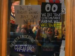 protestors are seen through a window in the senate chamber during dissuasion before a vote to redistrict the state s congressional map thursday dec 11 2025 at the statehouse in indianapolis