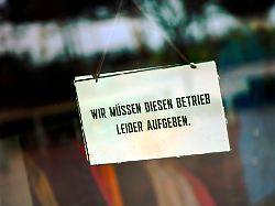 schild an der glastuer eines geschaefts mit der aufschrift wir muessen diesen betrieb leider aufgeben fotomontage