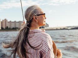 side view of mature woman wearing sunglasses and looking to the distance while standing on the yacht modellfreigabe vorhanden