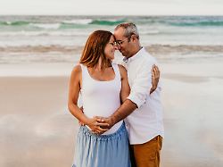smiling man taking care and embracing pregnant woman at beach model released symbolfoto ebbf08963