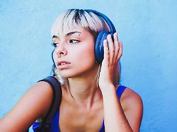 young woman with headphones and alternative style against blue wall model released symbolfoto svcf00567