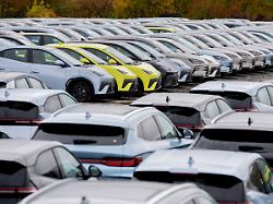 zahlreiche neue elektrofahrzeuge von byd stehen auf einem parkplatz im hafengebiet