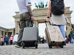 zwei touristen stehen mit ihren trolleys vor dem brandenburger tor berlin ist fuer viele reisende ein beliebtes reiseziel