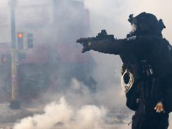 a minneapolis police officer aims a munition launcher amidst a thick cloud of teargas on nicollet avenue in minneapolis on saturday jan 24 2026