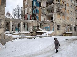 a woman walks on snow past an apartment building that was hit by a russian missile in june this year amid russia s attack on ukraine in kyiv ukraine december 31 2025