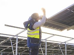 arbeiter bei installation von solarpaneelen im sonnenlicht auf metallgestell energiewende bau von pv freiflaeche baden wuerttemberg deutschland