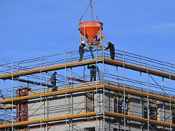 bauarbeiter auf einer grossbaustelle in muenchen betonkuebel betonieren beton wohnungsbau fassade eigentumswohnungen wohnbloecke baustoffe rohbau geruest