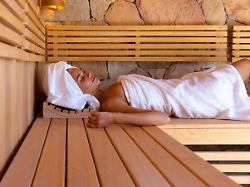 caucasian young woman in a bathrobe relaxing in the sauna