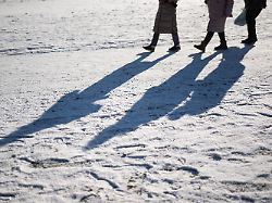 drei passantinnen gehen einen verschneiten weg entlang