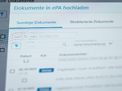 ein hausarzt laedt in seiner praxis dokumente in eine elektronische patientenakte epa