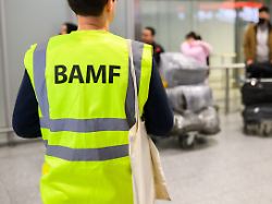 ein mitarbeiter vom bamf bundesamt fuer migration und fluechtlinge steht im flughafen hannover vor afghaninnen und afghanen aus den bundesaufnahmeprogrammen
