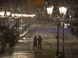 ein paar laeuft am fruehen morgen im schneetreiben durch die innenstadt