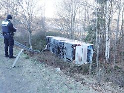 ein polizist filmt nach einem busunfall mit mehreren verletzten die ungluecksstelle der reisebus war auf die seite gekippt und einen abhang heruntergerutscht