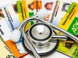 ein stethoskop liegt auf gesundheitskarten von verschiedenen krankenkassen als symbolbild fuer steigende krankenkassenbeitraege und notwendige reformen im gesundheitssystem