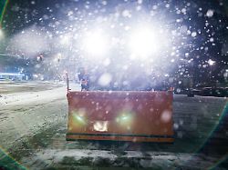 ein streufahrzeug steht am fruehen morgen im dichten schneefall im zentrum