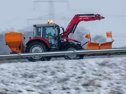 ein traktor mit schneepflug und streuvorrichtung ist auf einer nebenstrasse unterwegs eisregen schneefall und temperaturen um die null grad behindern den verkehr in norddeutschland