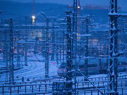 ein zug faehrt ueber das verschneite gleisvorfeld des hauptbahnhofs