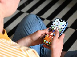 eine jugendliche sitzt auf dem boden und nutzt ein smartphone auf dem display sind verschiedene apps zu sehen