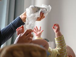 eine mutter haelt eine benutzte windel ueber ihrem baby am wickeltisch