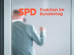 logo spd bundestagsfraktion mit abgeordneten in der unschaerfe
