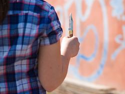 maedchen steht mit einem messer in der hand vor einer graffitiwand modellfreigabe vorhanden