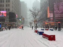 passanten gehen ueber eine verschneite strasse am times square ein heftiger wintersturm zieht derzeit mit klirrender kaelte schnee und eis ueber grosse teile der usa