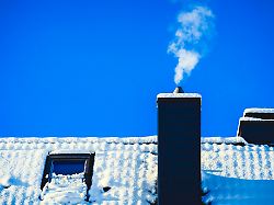 rauchender schornstein eines wohnhauses im winter