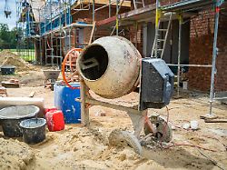 rohbau eines einfamilienhauses in laendlicher umgebung als altenteiler zu sehen sind ein aufgestelltes baugeruest steine sand und mischmaschine