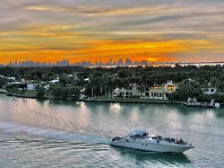 the sun sets behind the skyline of miami in a view of waterfront mansions on the island of la gorce seen from miami beach florida saturday january 21 2023