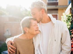 young man kissing grandmother forehead while standing with arm around at backyard model released symbolfoto property released meuf03129