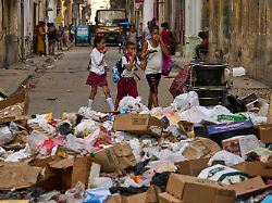 17 02 2026 kuba havanna menschen halten sich die nase zu als sie eine strasse mit muell passieren