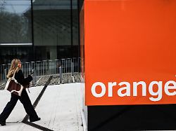 a woman walks next to the orange logo in front of the orange group headquarters in issy les moulineaux near paris on february 13 2025