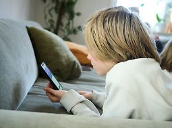 archiv 21 04 2025 bayern roth illustration ein junge liegt auf einem sofa und guckt auf sein smartphone gestellte szene