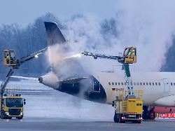 am flughafen muenchen wird in den fruehen morgenstunden ein flugzeug der airline lufthansa auf einer enteisungsflaeche von spezialfahrzeugen enteist
